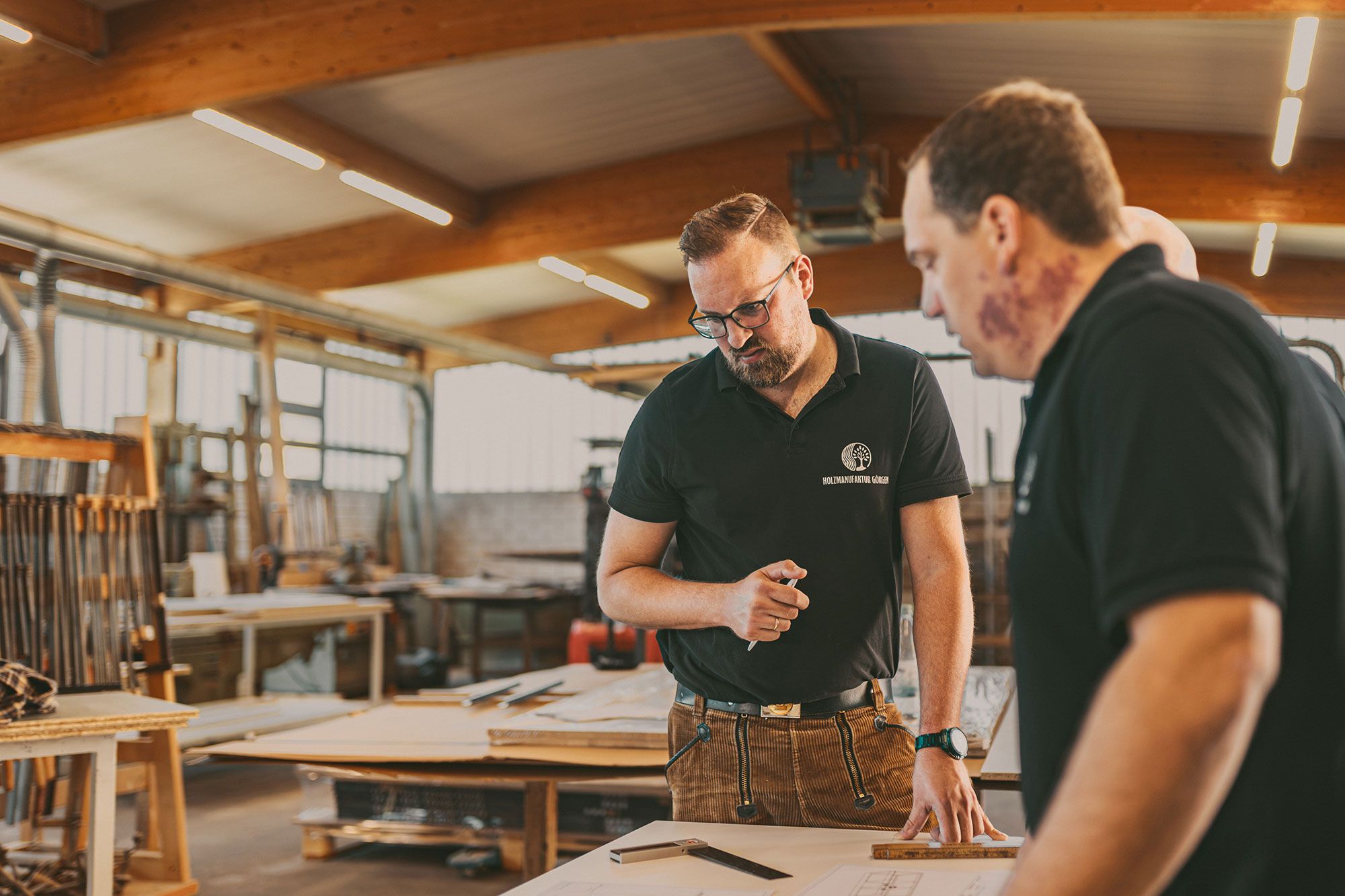 Kevin Görgen und ein Kollege besprechen Pläne für brandschutztechnische Maßnahmen in der Werkstatt
