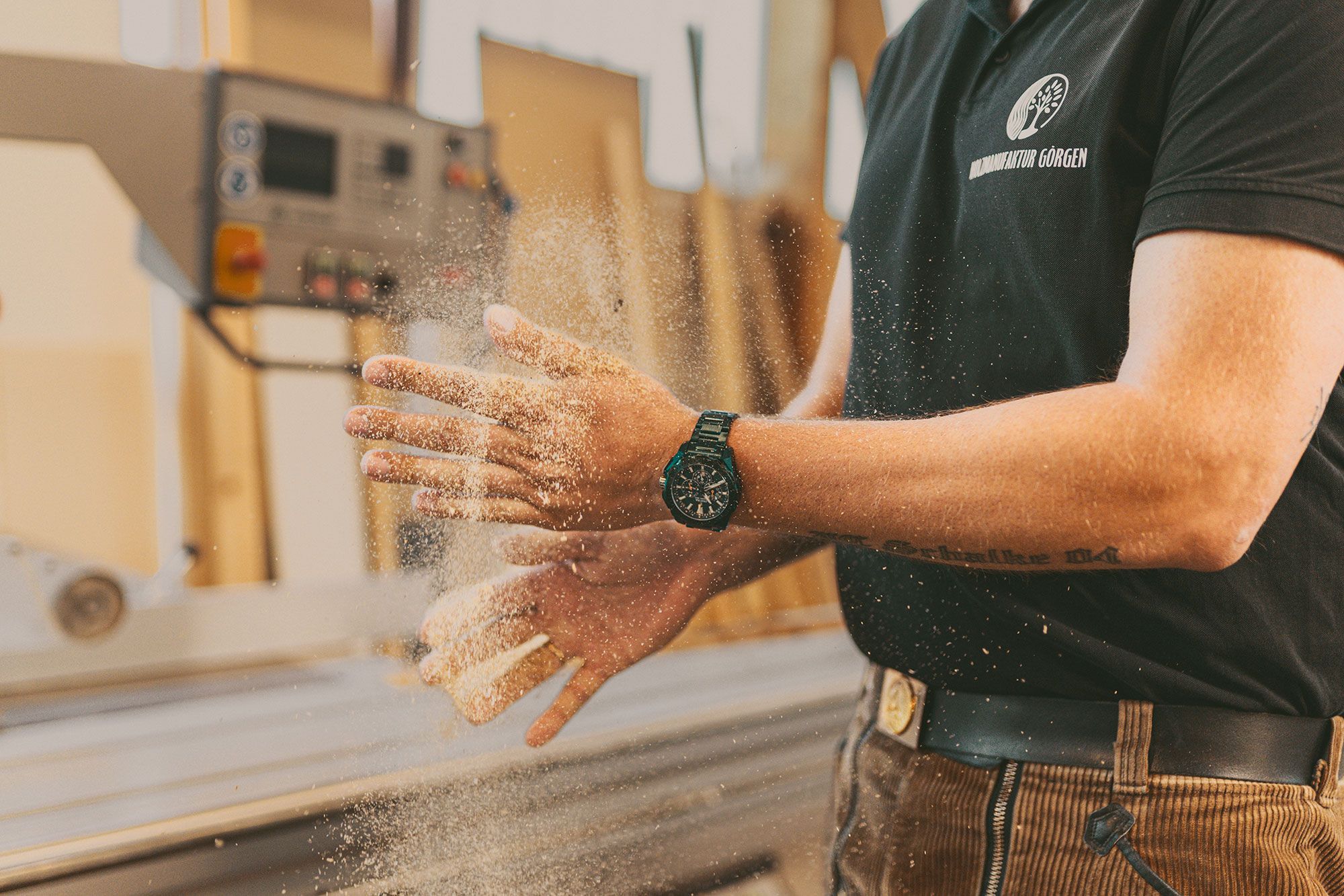 Tischler klopft sich in der Werkstatt der Holzmanufaktur Görgen Schleifstaub von den Händen